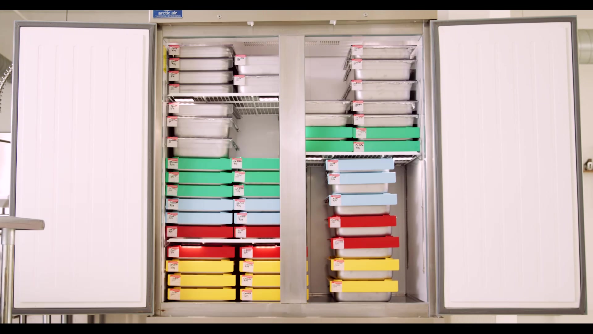 Color-coded pans arranged inside a commercial kitchen storage unit
