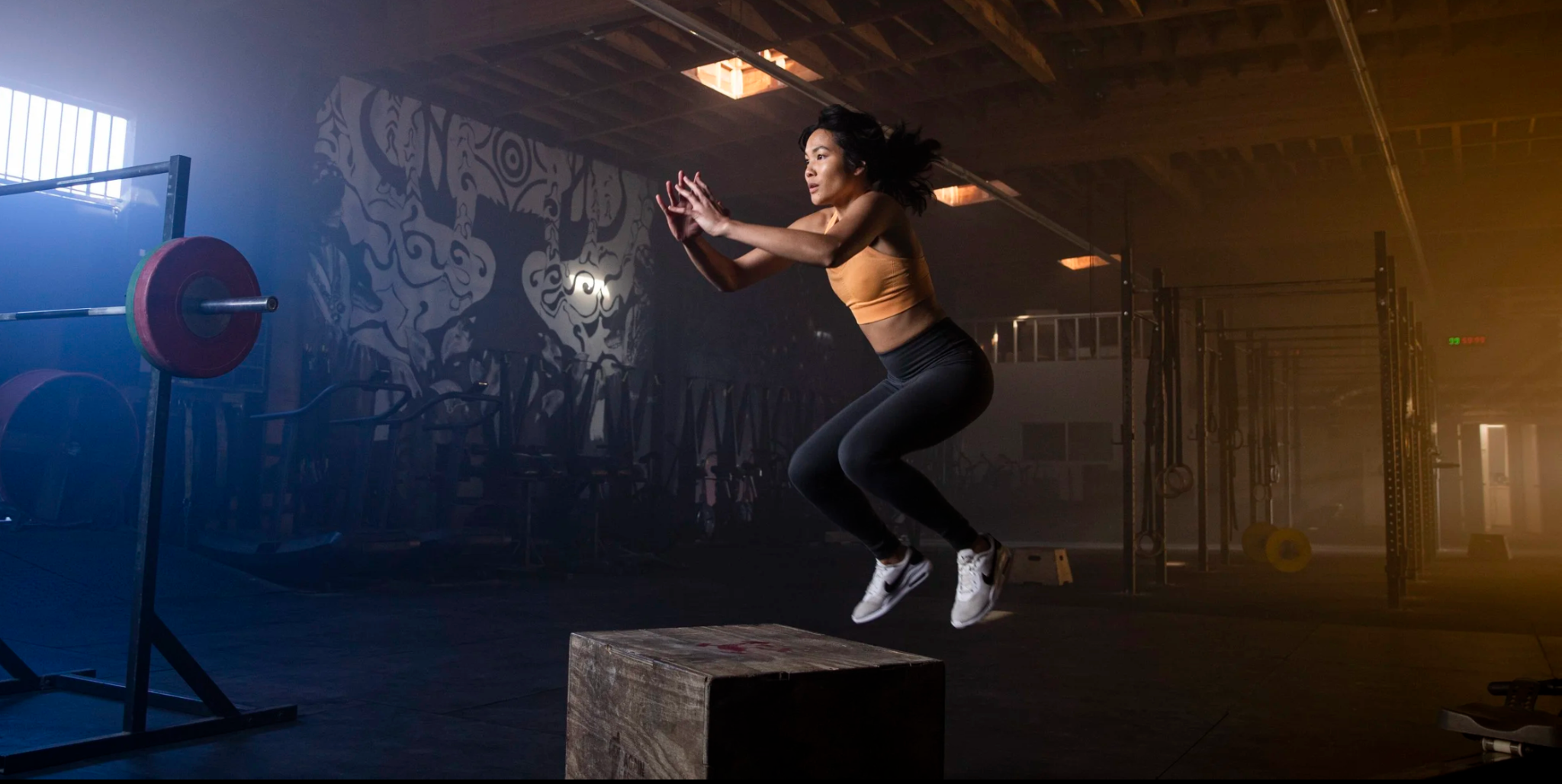 Athlete jumping onto a wooden box in a dramatic training space