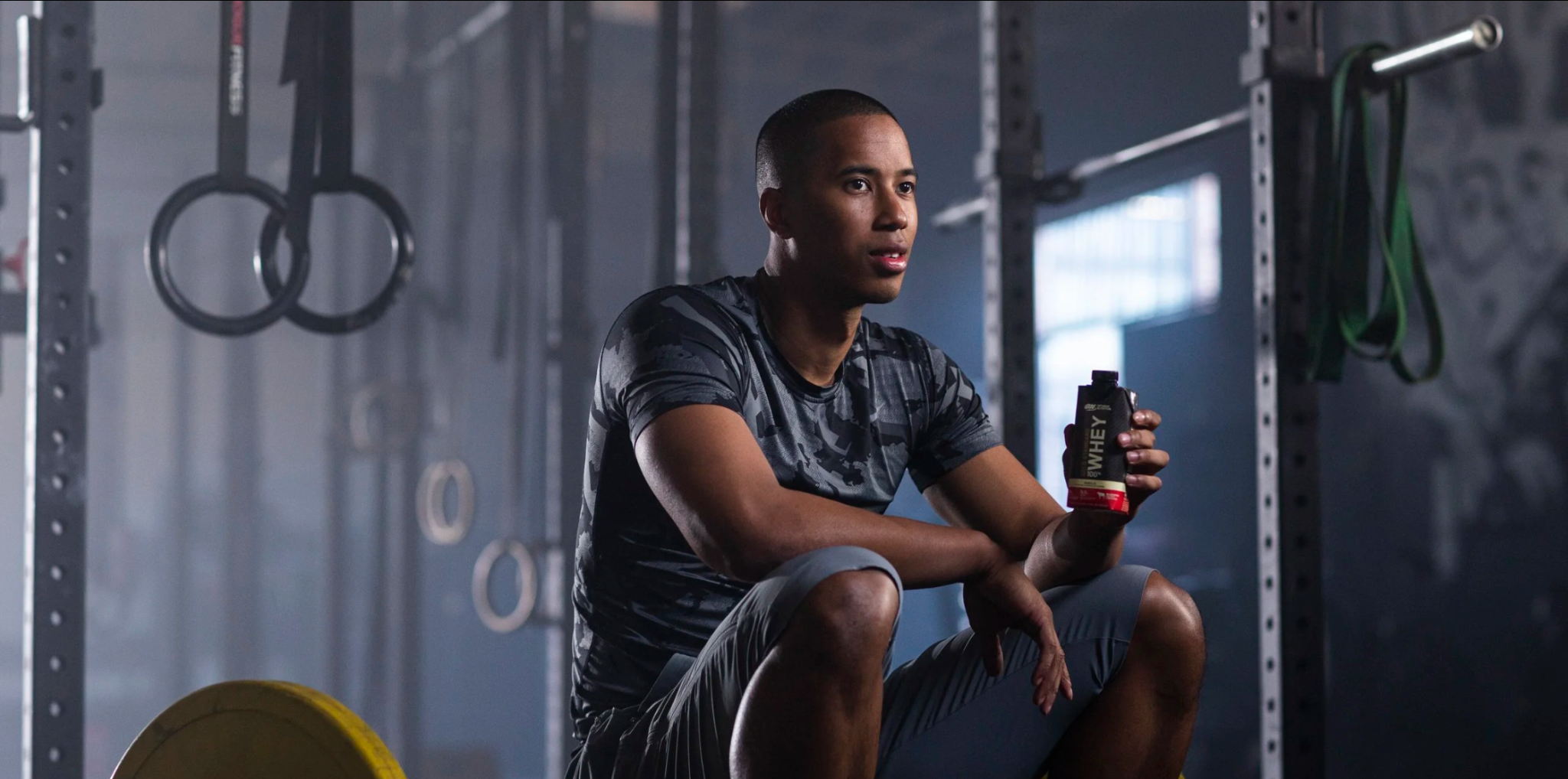 Athlete seated in a gym holding a bottle of protein drink