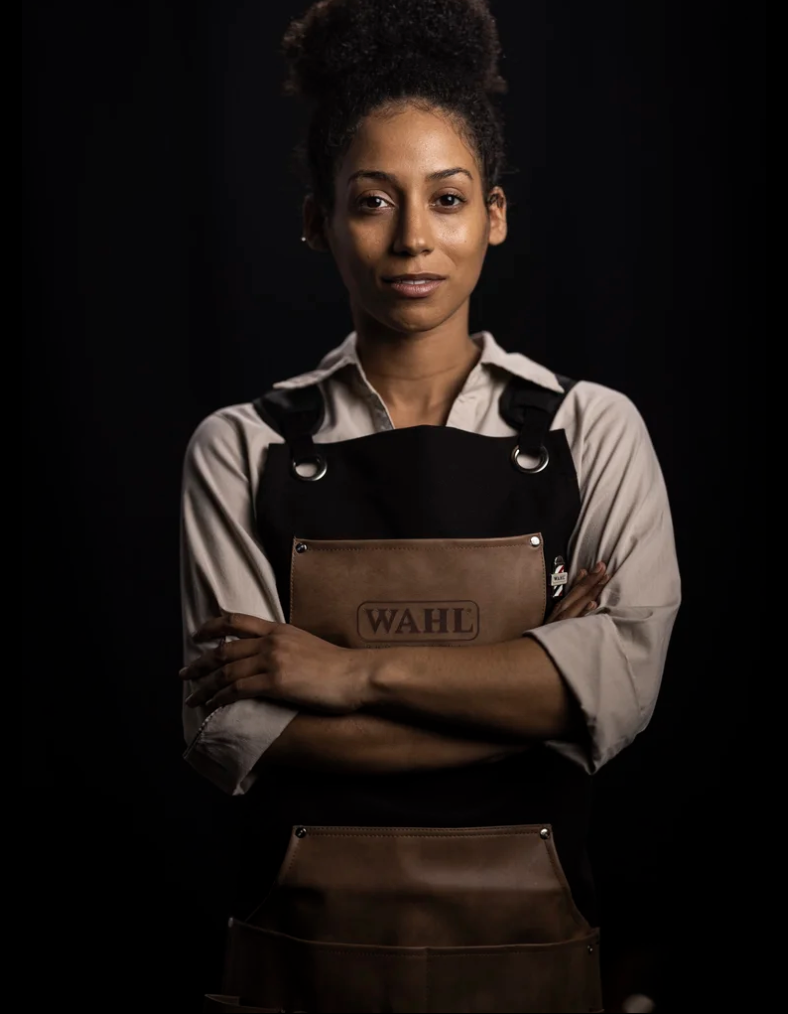 Wahl barber standing against a black background in a leather apron