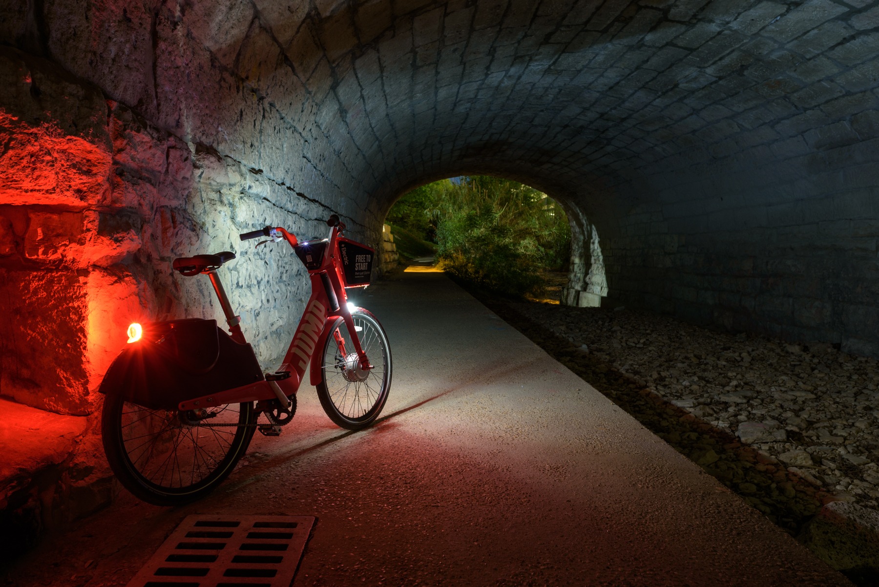 Bicycle illuminated by red light inside a stone tunnel