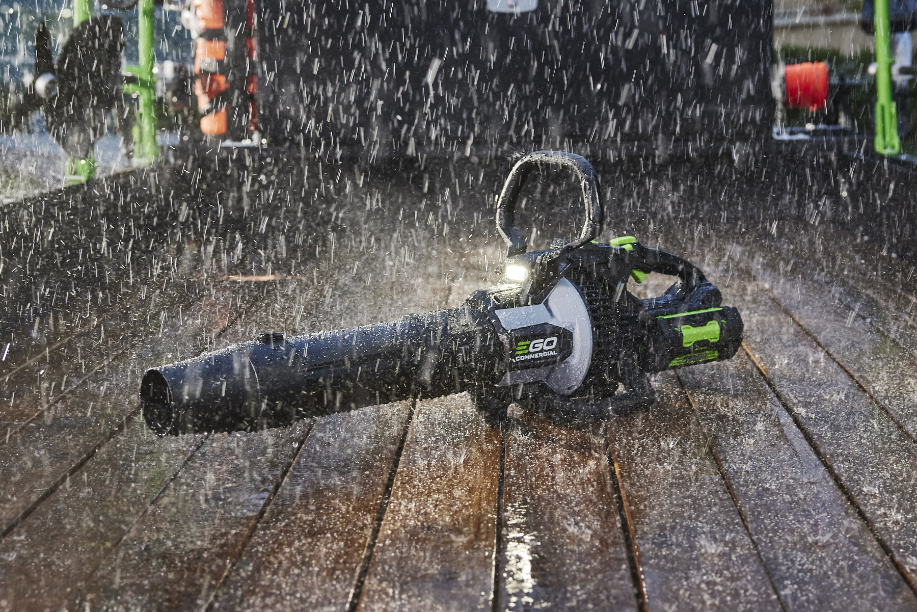 EGO leaf blower operating through heavy rain on a wooden deck
