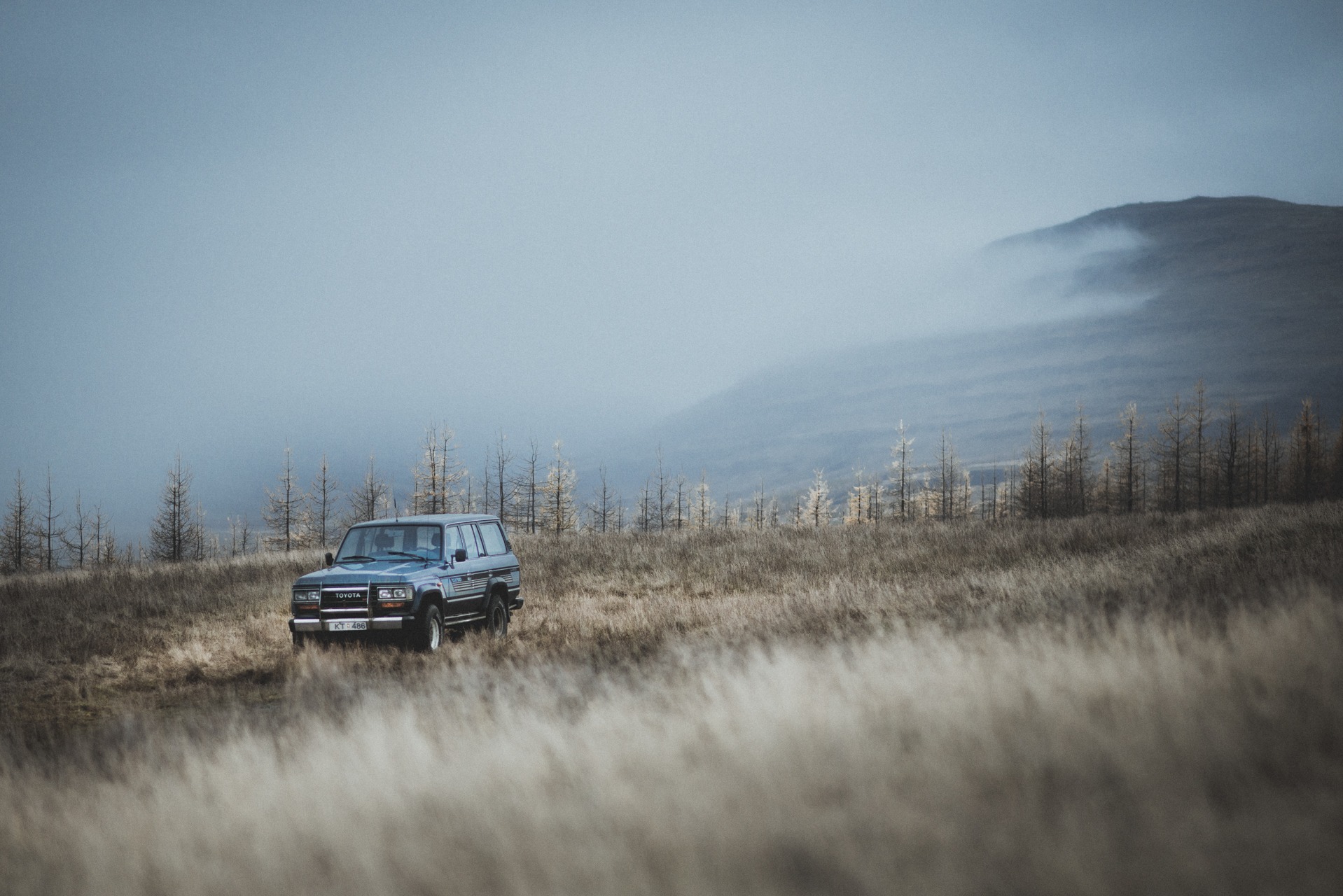 Classic car driving across a misty open landscape