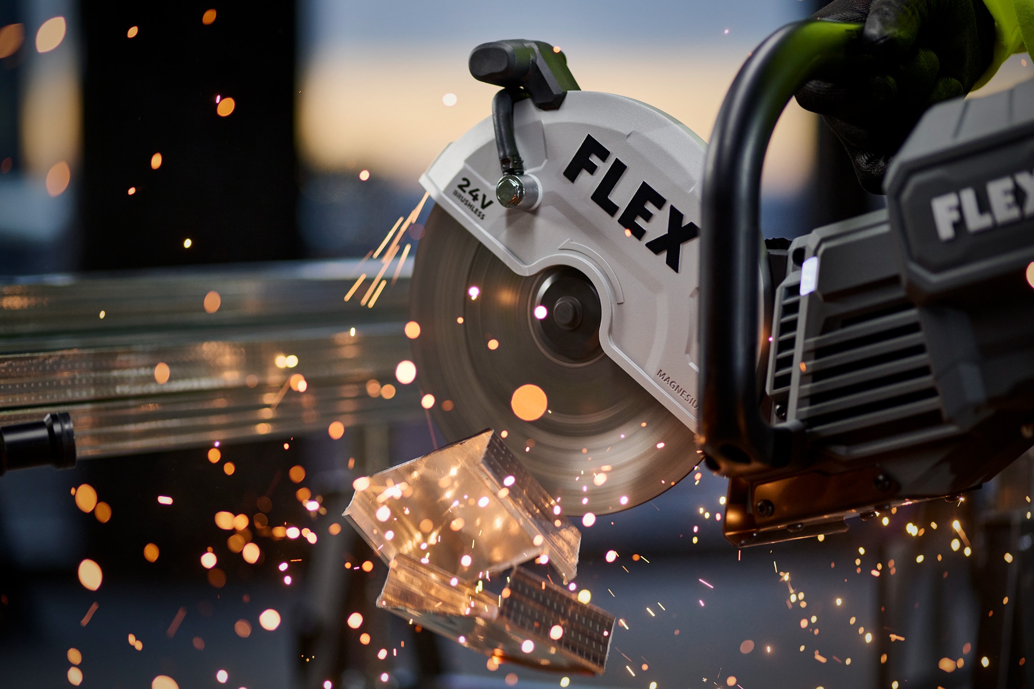 FLEX cutoff saw sending sparks across a dark workshop
