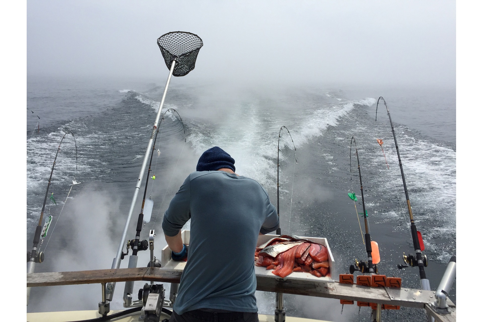 Angler fishing from a boat beneath dramatic storm clouds