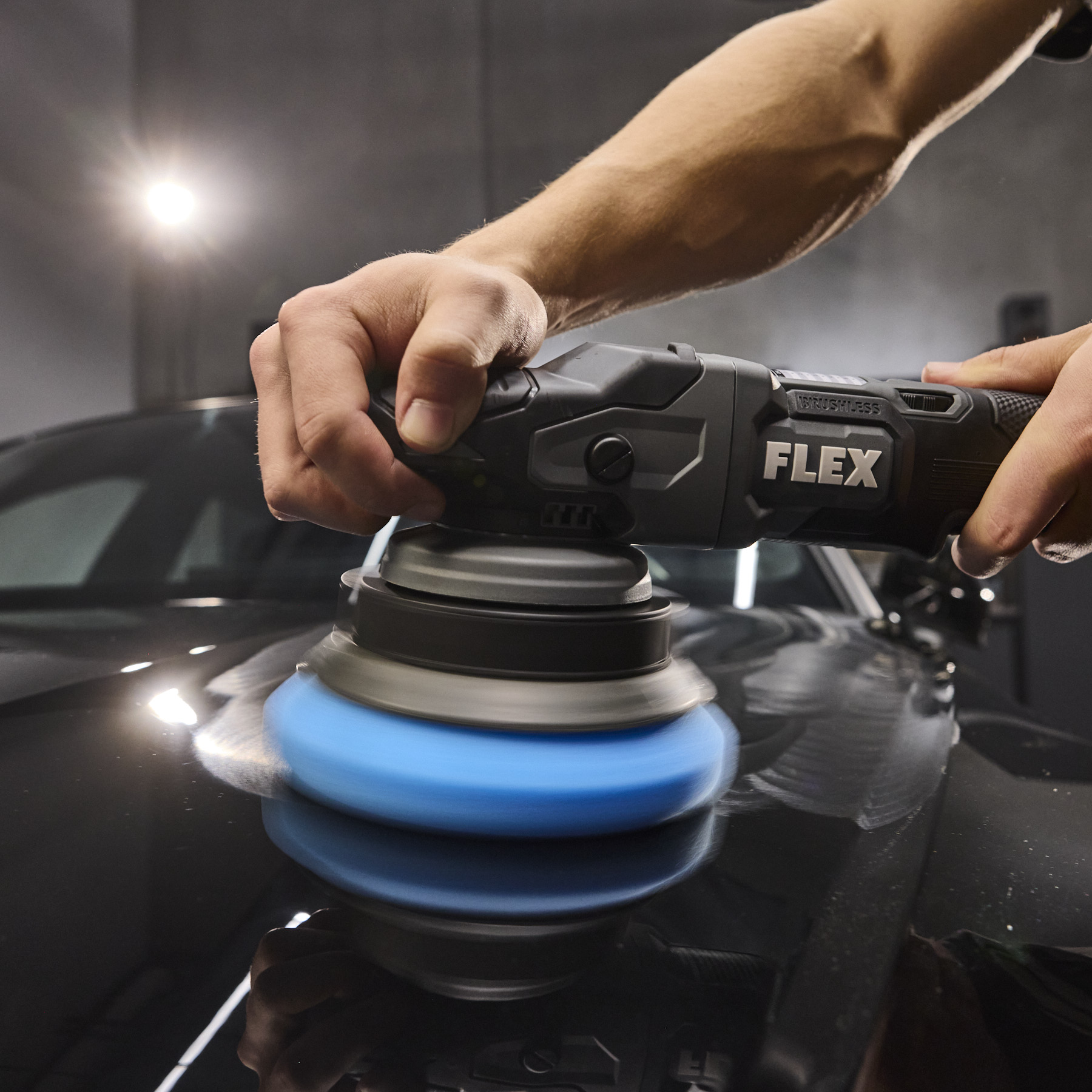 Hands guiding a FLEX orbital polisher across a car finish