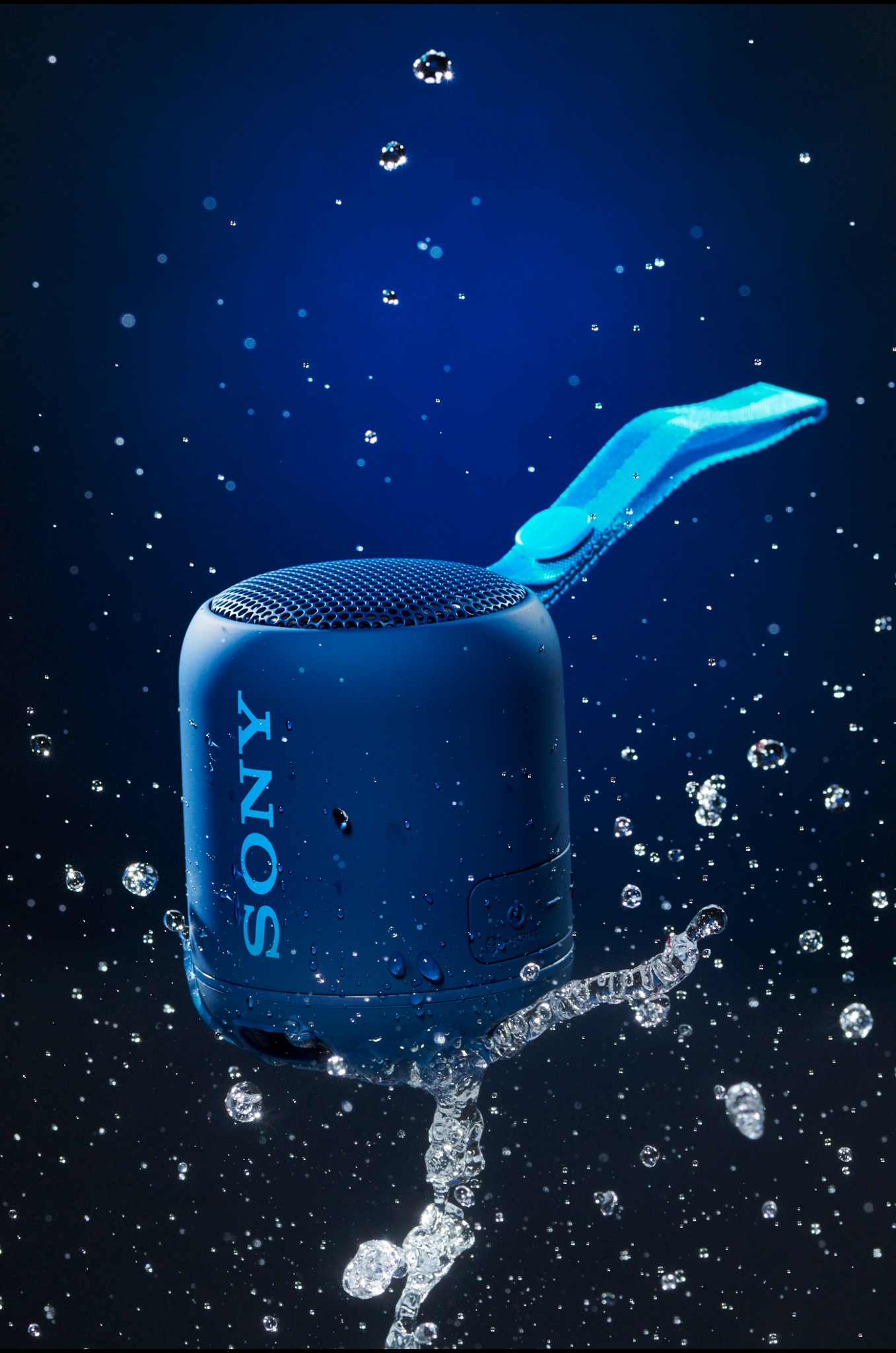Compact blue Sony speaker suspended among water droplets
